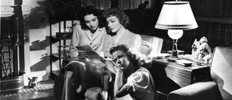 Colbert, Jones, Temple, stars of Since You Went Away, are pictured in a living room with Colbert reading a letter.